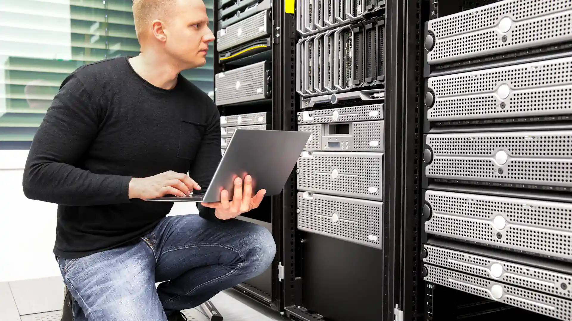 Consultant with laptop monitoring server in datacenter